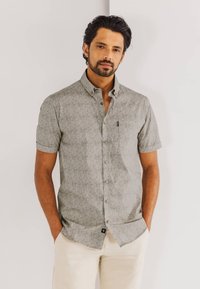 Korte mouwen, groen gemarmerd shirt met een knoopsluiting kraag, voorzien van een borstzak en een subtiele merketiket, gecombineerd met lichte beige broek.