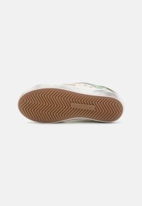 Sneaker with a textured rubber sole, featuring a white upper with green accents and yellow eyelets. Classic lace-up design, durable materials.