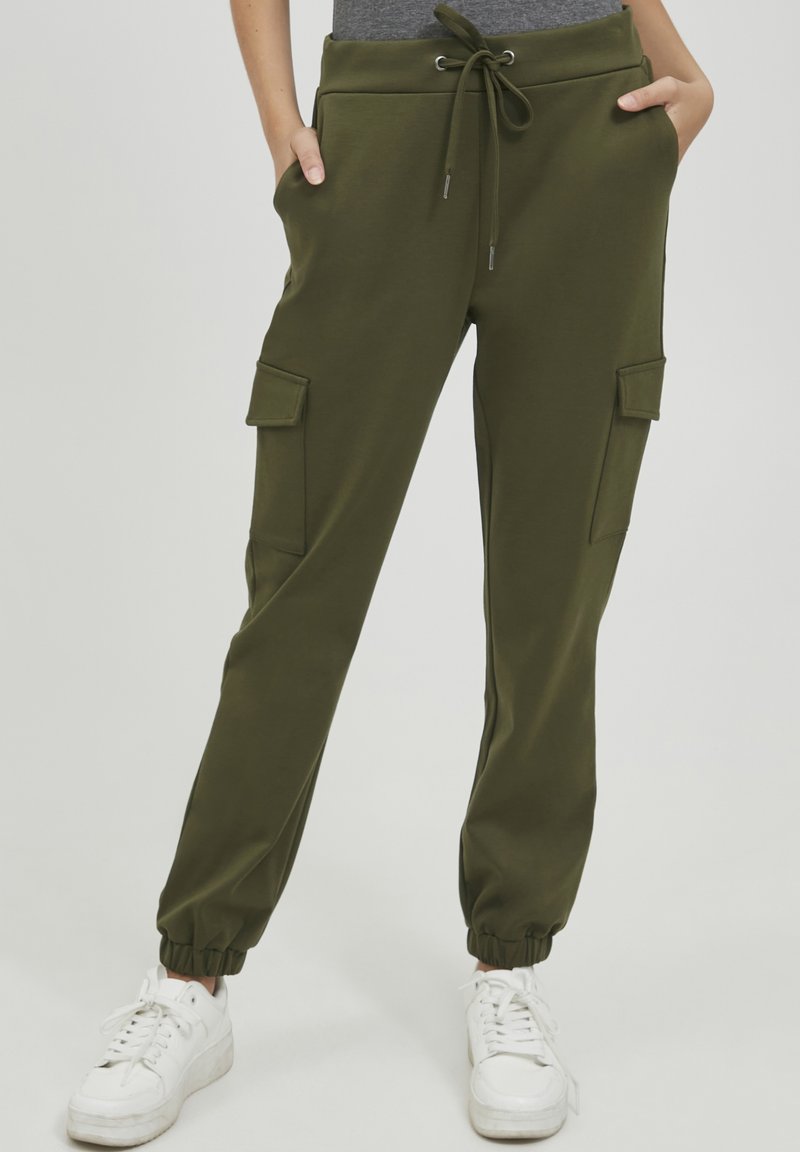 Olijfgroene cargo joggers met elastische boorden, een trekkoord tailleband en twee zijzakken met klepsluitingen. Glad stoffen textuur.