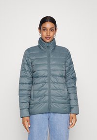 Casaco acolchoado em azul-turquesa com gola alta, costura vertical e fecho frontal. Apresenta bolsos laterais e uma textura suave e brilhante.