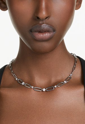 Collar de plata con eslabones alargados y piedras redondas transparentes, que presenta un diseño moderno y un acabado suave sobre la piel.