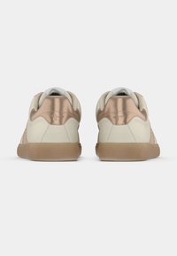 Baskets beiges avec accents rose gold, col rembourré et semelle en caoutchouc. Matière lisse avec détails cousus et design minimaliste.