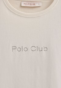 Biała bawełniana koszulka z krótkim rękawem z napisem "Polo Club" w małych srebrnych cyrkoniach, z okrągłym dekoltem i gładką fakturą. Metka wszyta w wewnętrzną stronę kołnierza.