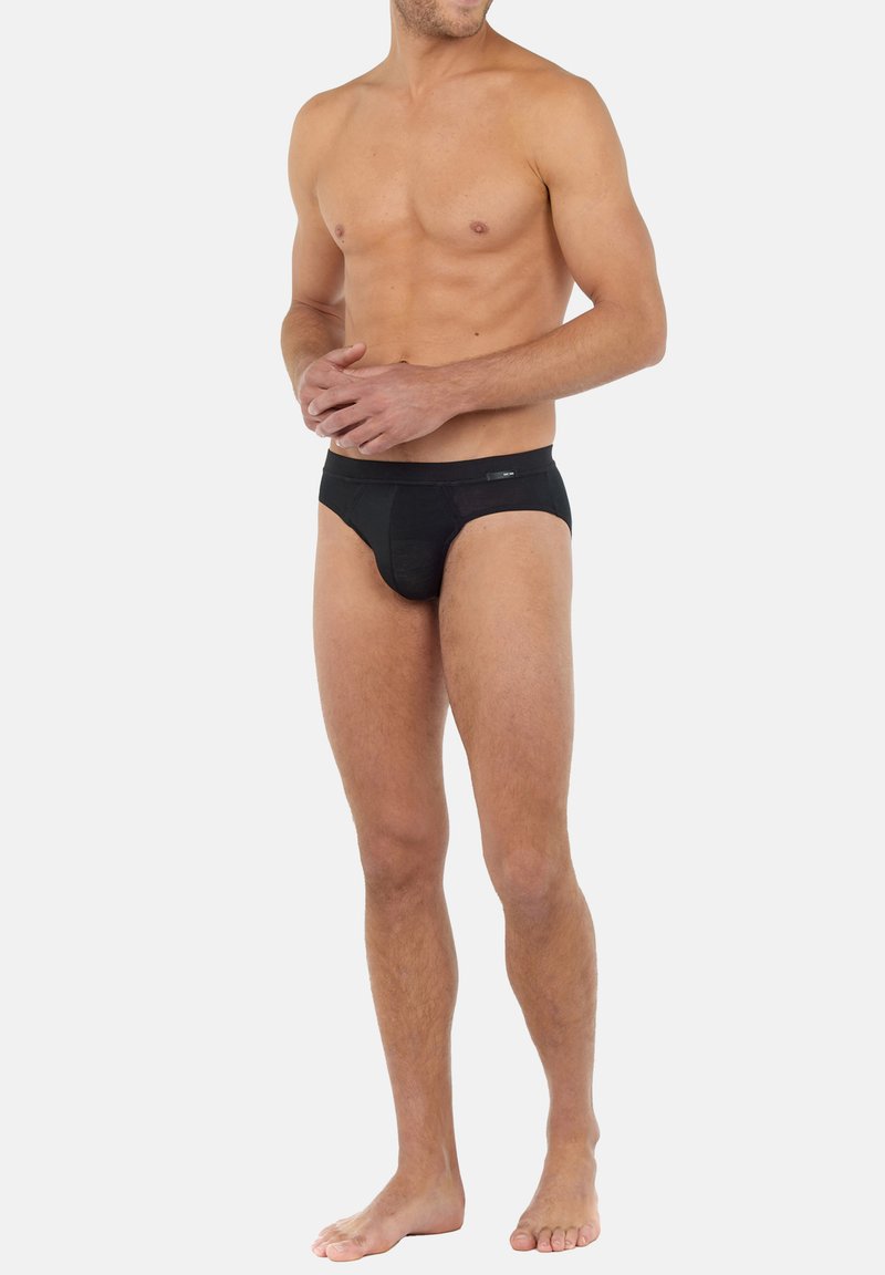 Schwarze Herrenunterwäsche aus einem weichen, dehnbaren Stoff. Mit einem tief sitzenden Bund und einer glatten Oberflächenstruktur. Minimale Details auf der Vorderseite.