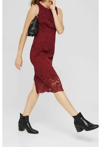 Bordeauxkleurige kanten midi-jurk met bloemmotief, zijsplit, gecombineerd met zwarte enkellaarsjes en een zwarte schoudertas. Soepele stofstructuur.