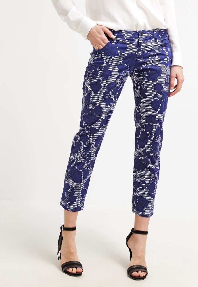 Mellanhöga cropped byxor i ett marinblått blommönster med en texturerad bakgrund. Har en figurnära design och diskreta fickor.