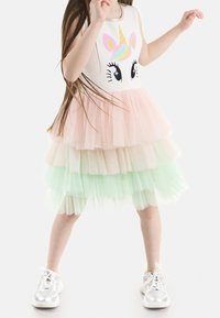 Gestuftes Tüllkleid mit einem Einhorn-Design. Verfügt über ein weißes Oberteil, Stufen in Rosa und Mintgrün sowie einem ärmellosen Schnitt. Sichtbare silberne Sneakers.