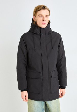 Parka negra impermeable con un collar alto, capucha ajustable, bolsillos frontales y cierre de cremallera/botón. Tejido suave con un acabado mate.