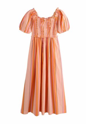 Ung kvinde med langt brunt hår iført en pink og orange stribet kjole med puffede ærmer mod en ensfarvet baggrund.