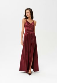 Burgundská saténová maxi šaty s výstřihem do V, tenkými ramínky, obtočeným svrchním dílem a bočním rozparkem; hladká textura a jemný lesk.