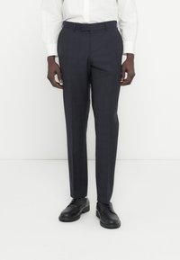 Tamsiai mėlyni languoti kelnės iš lygaus audinio, pritaikytu kirpimu, su diržo kilpų juosmeniu, segamos virš juodų batų.