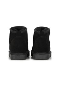 Botines de ante negro con un suave forro interior, puntera redondeada y suela de goma plana. En la parte trasera tienen una simple pestaña para facilitar su uso.