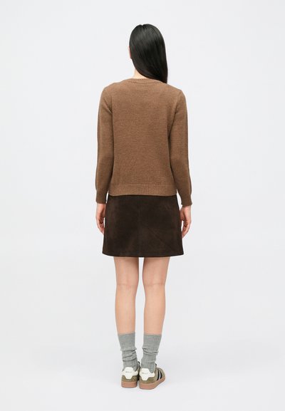 Pruun kootud kampsun soonikkoes äärega, kombineeritud tumepruuni seemisnahast seeliku, hallide soonikuga sokkide ja valget aktsenti kandvate tossudega.