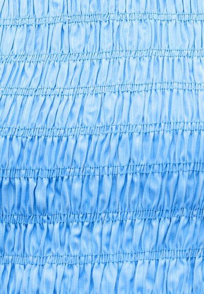 Ανοιχτό μπλε ύφασμα με οριζόντιες σειρές ραφής με ελαστικό, δημιουργώντας ρυτιδωτή υφή.