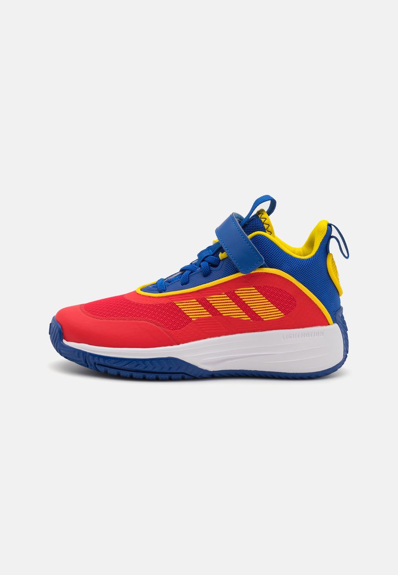 Baskets rouges, bleues et jaunes avec tige en mesh, sangle en Velcro, semelle texturée et motif de rayures contrastantes. Conception légère.