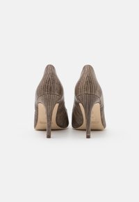 Zapatos de tacón alto con un exterior de cuero en un tono topo oscuro texturizado, que presenta un sutil patrón de reptil y un elegante diseño de punta afilada.