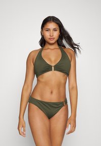 Alyvuogių žalios spalvos bikinio komplektas su kaklo viršumi, kuriame yra centrinis susiraukimas ir auksinės spalvos detalės, derinamas su žemais kelnaitėmis. Lygus tekstūra.