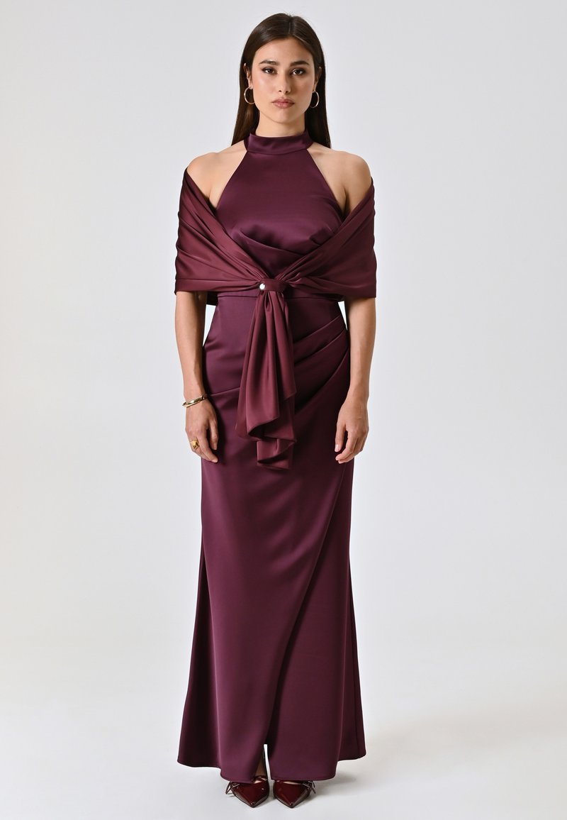 Long burgundy dress in satin with a high collar, off-shoulder sleeves, and a twisted waist detail. Features a matching shawl and beaded accents.