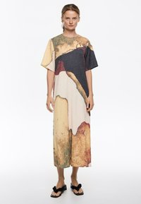 Vestido de corte relajado hecho de tela texturizada. Presenta una mezcla de patrones abstractos en beige, negro y verde, con una longitud a media pantorrilla y mangas cortas.