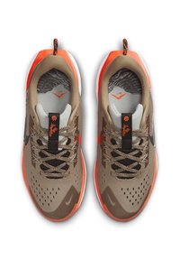 Zapatillas deportivas ligeras con parte superior de malla beige, detalles en naranja, plantillas con patrones y suelas flexibles con cordones multicolores.