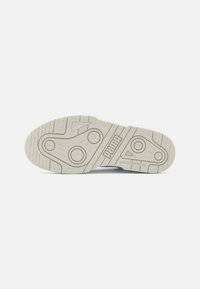 Hvid gummisål til sneakers med et tekstureret mønster og cirkulære accenter. Logo synligt i midten. Har riller for bedre greb.