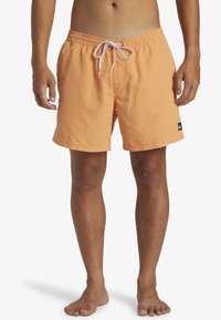 Bañadores naranjas con cintura elástica y cordón blanco. Cuenta con bolsillos laterales y un pequeño logo negro de la marca en el dobladillo.