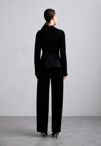 Top negru, croit, cu textură ribbed, asociat cu pantaloni largi negri. Ambele articole au un design elegant, minimalist.