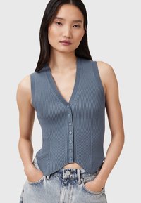 Blau gerippter ärmelloser Oberteil mit V-Ausschnitt, ausgestattet mit einer Knopfleiste und einem gekürzten, leicht ausgestellten Saum. Kombination mit hochtaillierten Jeans.