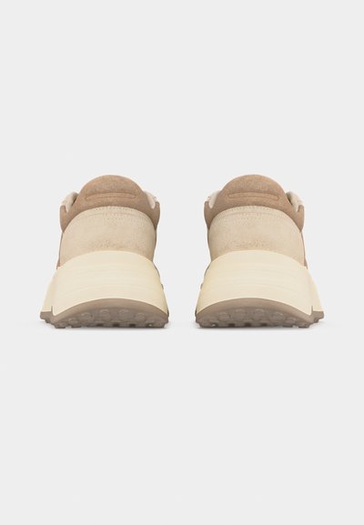 Paire de baskets beige et marron clair avec des semelles épaisses blanc cassé, vues de dos sur un fond blanc uni.