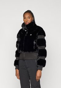 Jacket de pêlo preto com um colarinho alto, apresentando uma mistura de painéis brilhantes e texturizados. Punhos e hem com malha canelada e fecho de zip.
