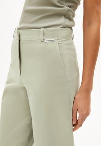 Hellgrüne Hose aus glattem Stoff, mit geradem Schnitt, seitlichen Taschen und einem ARMENANGELS-Label am Bund.