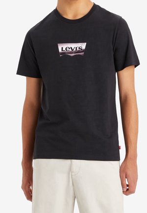 Svart kortärmad t-shirt i bomull, med en grå Levi's logotyp centralt på bröstet. Minimalistisk design, klassisk passform.