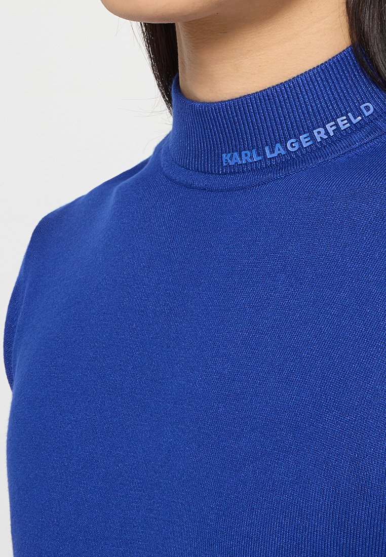 Blaues Oberteil mit hohem Kragen aus glattem Stoff. Es hat einen gerippten Kragen mit dem "KARL LAGERFELD" Logo in kontrastierendem Blau auf der Vorderseite.