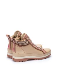 Botas de tobillo de cuero beige con un collar acolchado, herrajes metálicos para los cordones y acentos en rosa, que cuentan con una suela estriada para mayor tracción.