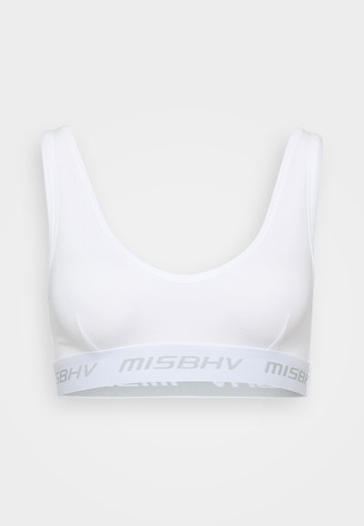 White sports bra with a scoop neckline, wide straps, and a branded elastic band featuring light gray lettering. Smooth fabric texture.