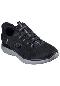 Baskets de sport noires avec une tige en mesh respirant, des lacets élastiques et une semelle grise rembourrée. Présente des accents et un branding gris subtil.