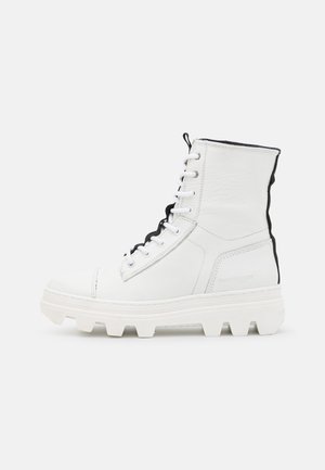 Witte hoge leren laars met dikke profielzool, zwarte voering, witte veters en trekriempje aan de achterkant.