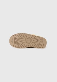 Sole of a shoe with a textured rubber surface, featuring a circular pattern at the center and angular designs radiating outward.