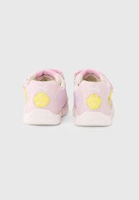 Ténis rosa com acabamento liso, apresentando detalhes amarelos e um calcanhar com padrão. Tira de velcro e sola de borracha texturizada para aderência.