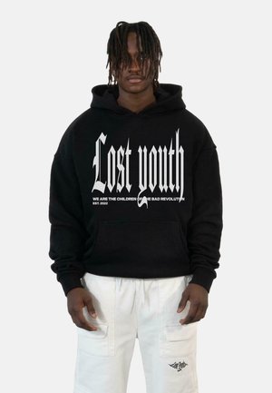 Hoodie oversize noir avec du texte gothique blanc "Jeunesse perdue" et un slogan. Comprend une poche à l'avant et une texture douce.