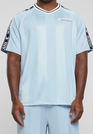 Vaaleansininen urheilupaita, jossa on pystysuorat raidat, V-kaula-aukko ja mustat yksityiskohdat hihoissa, joissa on logo. Valmistettu sileästä, hengittävästä kankaasta.