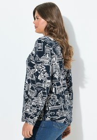 Blaues Langarmshirt mit einem weißen Hausmotiv. Es hat eine lässige Passform und einen runden Ausschnitt. Strukturierter Stoff für zusätzlichen Komfort.