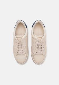 Beige Leder Sneaker mit navy Akzenten, runder Zehenpartie, flacher Gummisohle und beigen Schnürsenkeln. Logo auf der Ferse und Zunge geprägt.