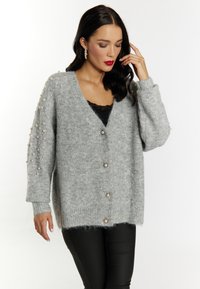 Cardigan tricotat gri, cu o croială lejeră, având embellisamente din perle pe mâneci, decolteu în formă de V și nasturi decorativi.