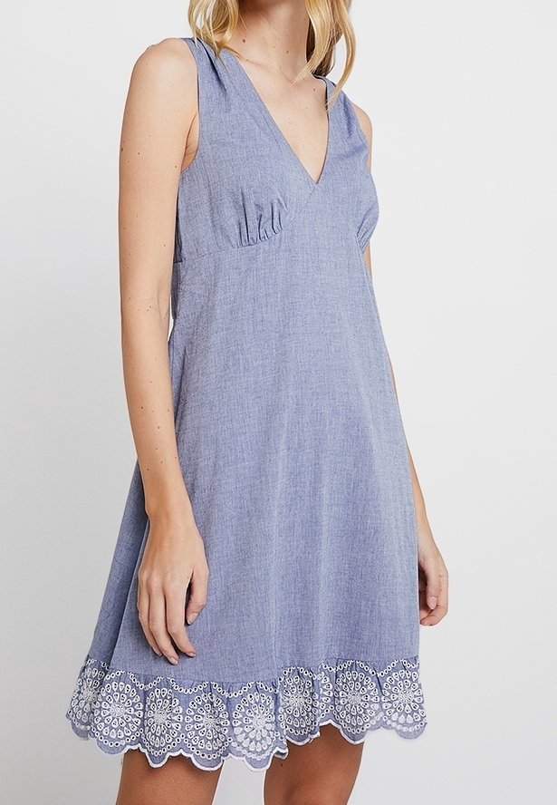 Blaues Chambray-Ärmelloses Kleid mit V-Ausschnitt, raffinierten Details und weißem besticktem Spitzenabschluss. Weicher Stoff und A-Linie-Silhouette.