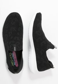 Mustat liukusukat, joissa on teksturoitu, hengittävä verkko-osa, valkoinen kumi-ulkopohja ja värikäs brändilogo pohjallisessa.