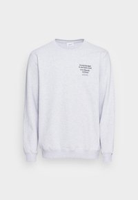 Sudadera gris claro hecha de un material suave con cuello redondo. Presenta texto en la parte frontal en negro que dice: "Un buen diseño no es solo algo genial..."