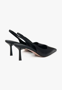 Zwarte leren slingback schoenen met een puntige neus en slanke hakken. Soepele textuur met minimale details, wat een elegante silhoutte laat zien.