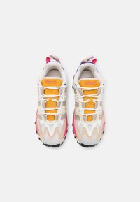 Buty sportowe z białą i różową cholewką, żółtym językiem i czarną podeszwą. Charakterystyczne sznurowanie i teksturowane panele.