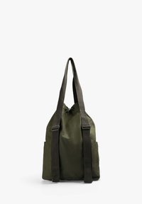 Mochila de lona verde oliva con correas oscuras ajustables, cierre de cordón, dos bolsillos laterales y una forma estructurada.